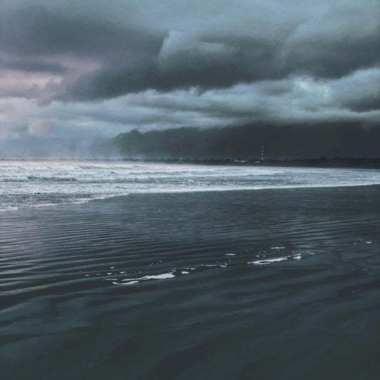 Stormy sky over a body of water with dark clouds and reflective water surface.
