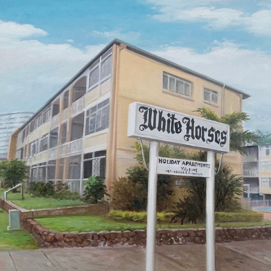 Multistory building with 'White Horses Holiday Apartments' sign in front