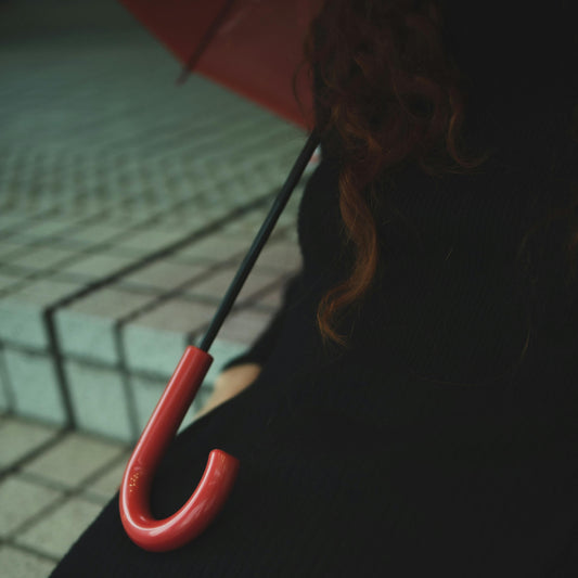 Red umbrella handle held by a person with a blurred background