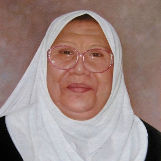 Person wearing a white headscarf and pink glasses against a plain background