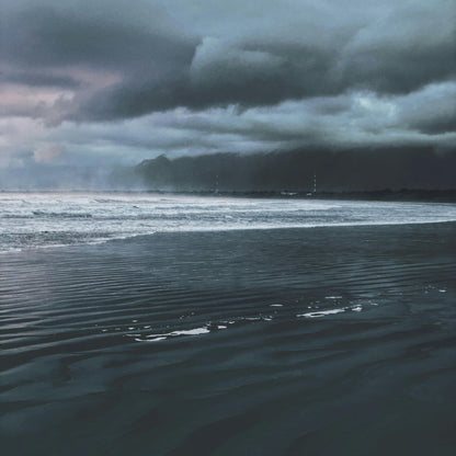 Stormy sky over a body of water with dark clouds and reflective water surface.